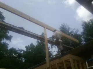 Carpenter setting a ridge beam over a new addition frame — Ice Dam Removal by Roofing Brothers in Mcdonough