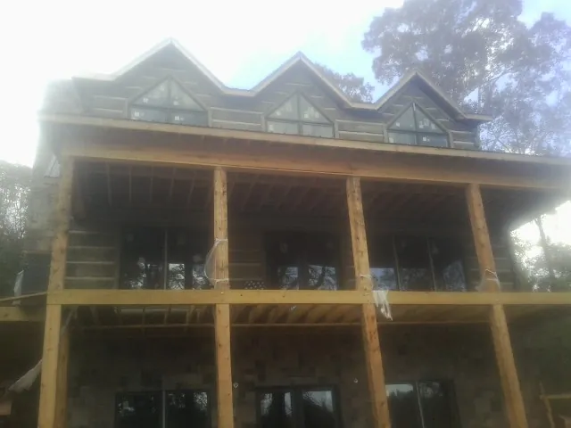 Dormers and porch framing on a large log home under construction — Roof Coating work by our crew in Mcdonough