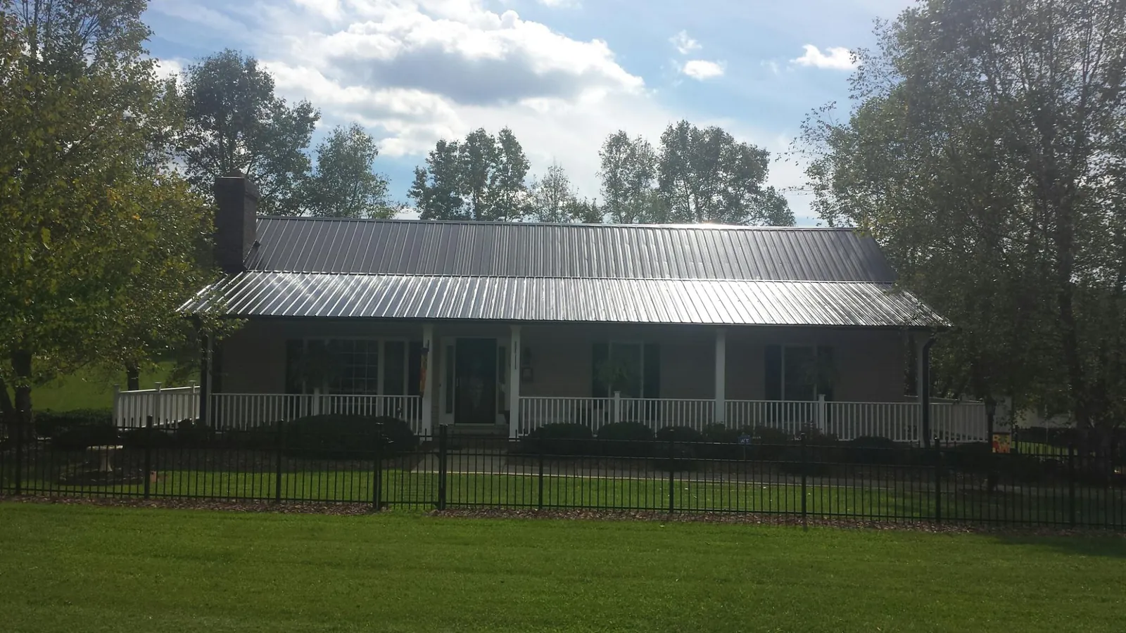 Gray metal roof on a brick ranch with a full width front porch — Gutter Guard Installation work by our crew in Mcdonough