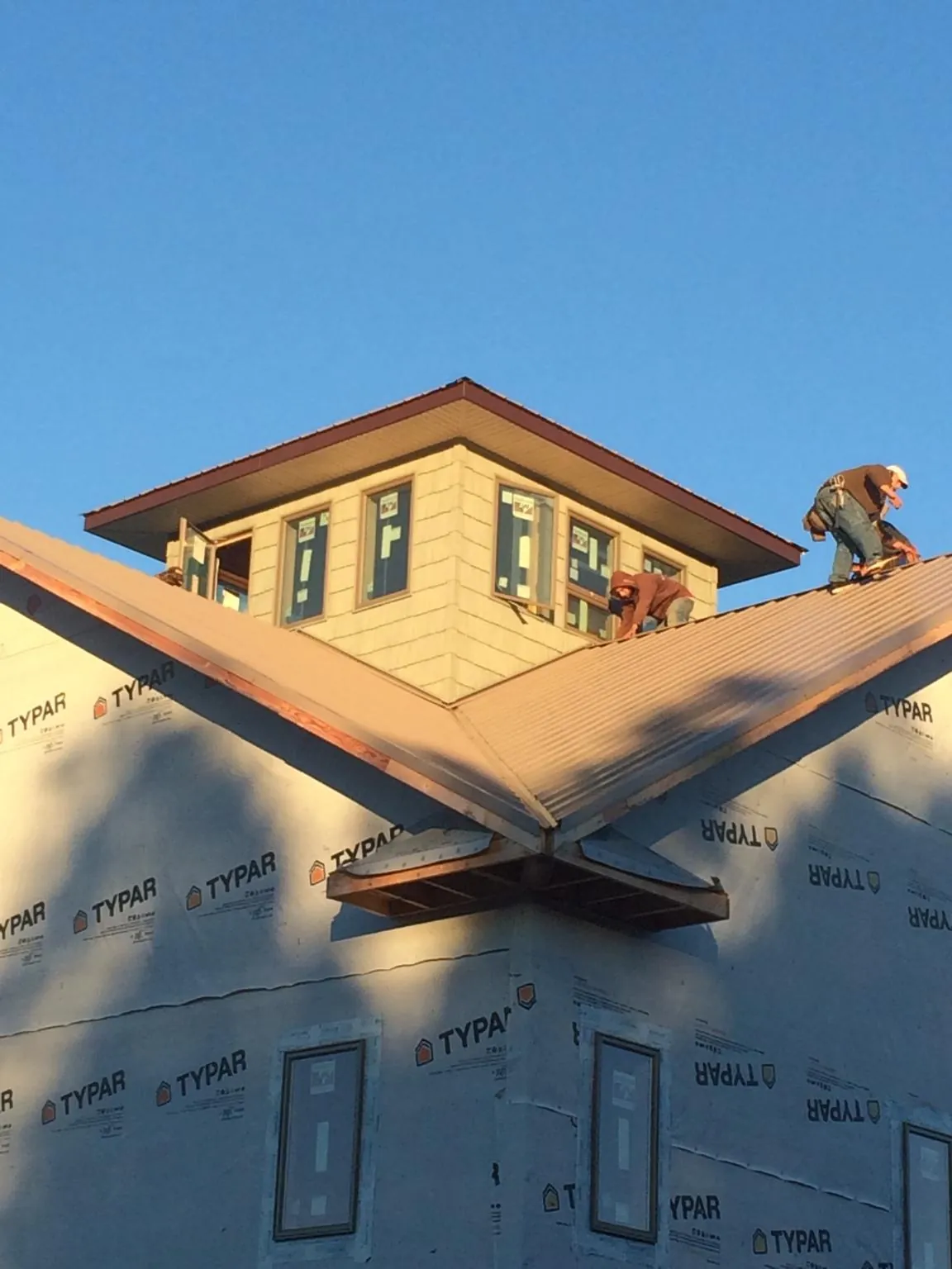 Roofers working around a rooftop cupola on a new metal roof at sunset — Roof Waterproofing in Mcdonough by Roofing Brothers